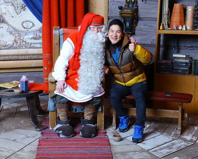 Santa Claus of Rovaniemi posing for a picture with a person. Photo.